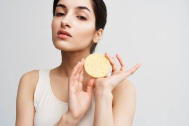 Elinde süngerle esmer, temiz cilt bakımı kozmetik.