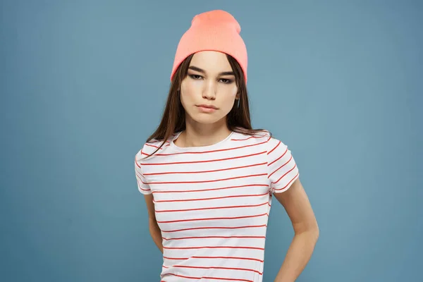 Vacker kvinna i randig t-shirt rosa hatt mode blå bakgrund — Stockfoto