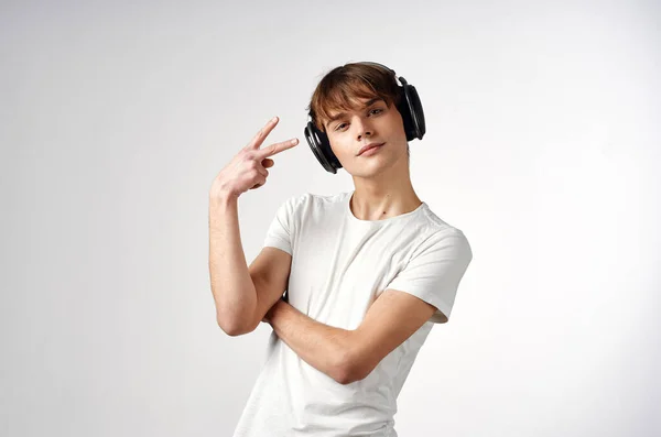 Ragazzo in t-shirt bianca con cuffie musica tecnologia luce sfondo — Foto Stock