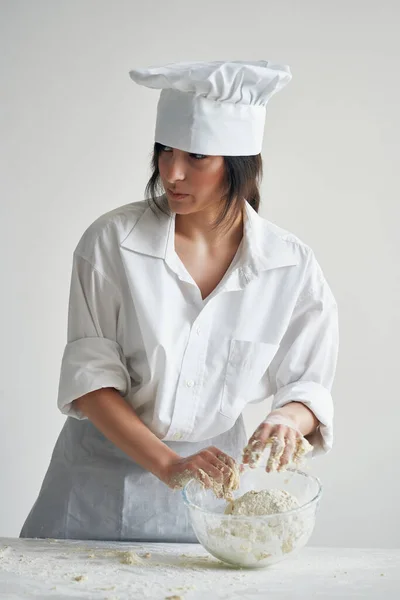 woman chef baker rolls out dough flour cooking work