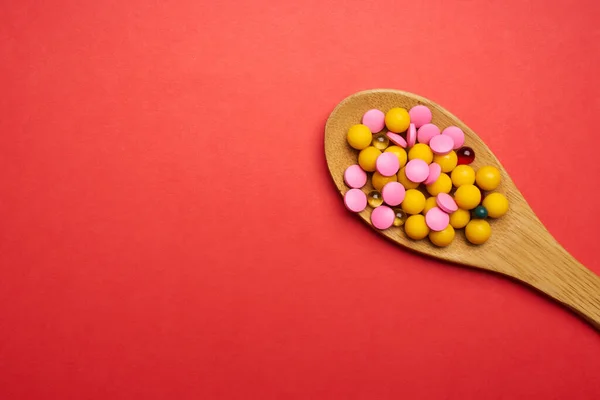 Таблетки в ложке на красном фоне вид антибиотиков — стоковое фото