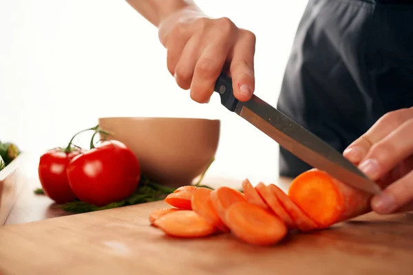 Affettare le carote su un tagliere con un coltello cottura di verdure fresche — Foto Stock
