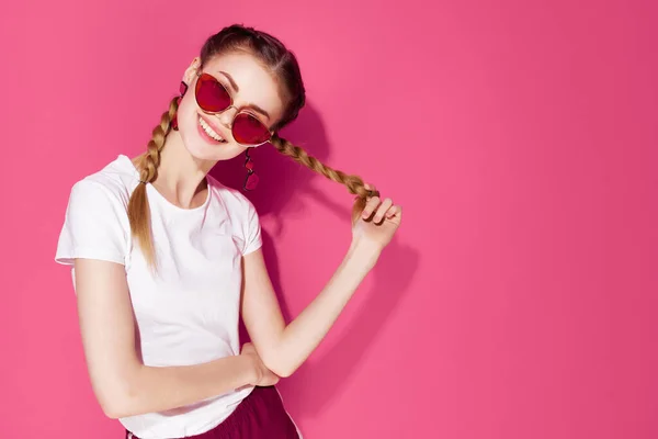 Aantrekkelijke vrouw dragen zonnebril in wit t-shirt mode levensstijl roze achtergrond — Stockfoto