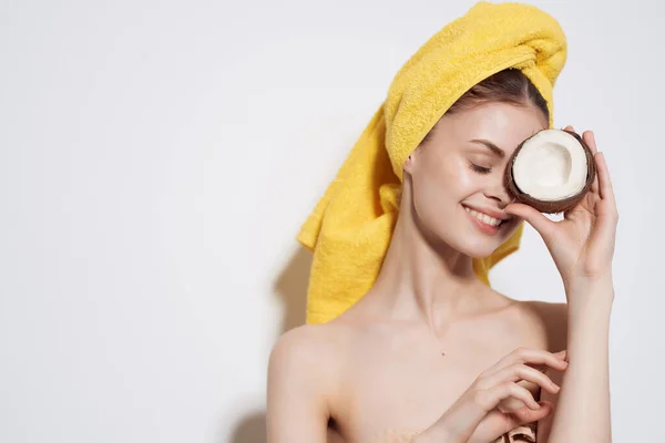 Wanita dengan bahu telanjang handuk kuning di kepalanya kelapa memegang buah kulit bersih — Stok Foto