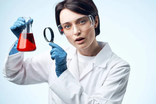 Donna scienziata guardando attraverso una lente di ingrandimento a una soluzione chimica di lavoro biotecnologia — Foto Stock