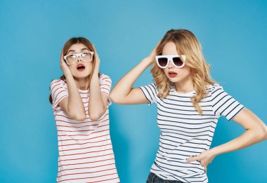 İki kadın çizgili tişörtler içinde yan yana durur. Çekici görünürler. Mavi arka plan.