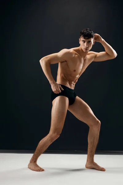 Athletic man with a pumped up naked torso in dark panties posing — Stockfoto