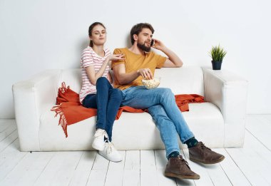 Kadın ve erkek evde kanepede patlamış mısırla film seyrediyor.