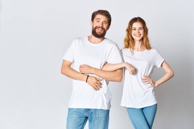 Beyaz tişörtlü bir adam ve kadın stüdyo tarzı poz veriyorlar.