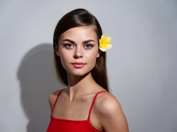 Pretty woman in red t-shirt with yellow flower in hair cropped view — Stockfoto