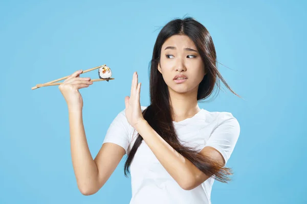 Женщина в белой футболке палочки для еды суши роллы японская кухня — стоковое фото