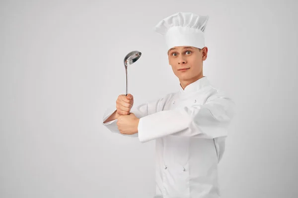 Vidám férfi szakács konyhai eszközökkel Szakmai fény háttér — Stock Fotó