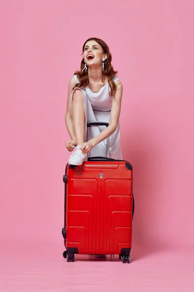 Женщина туристы в белом платье с красным чемоданом стиль жизни пассажира розовый фон — стоковое фото