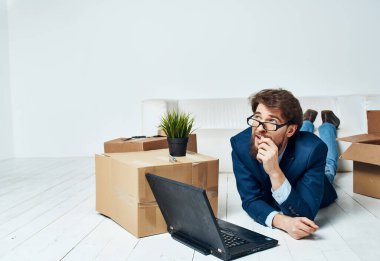 Ucuz bir adam dizüstü bilgisayarın önünde yerde yatıyor. Çalışma yerini değiştiriyor.