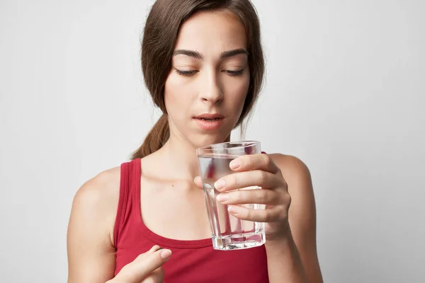 Femme en t-shirt rouge verre d'eau prendre des médicaments mode de vie traitement — Photo