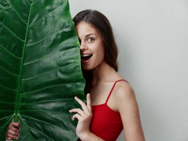 Kırmızı mayo giymiş, palmiye yapraklı kadın egzotik manzaralı.