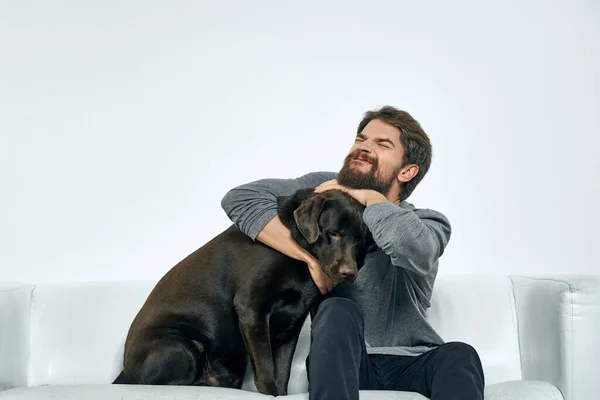 Hombre alegre jugando en casa en el sofá con el perro emociones divertidas — Foto de Stock