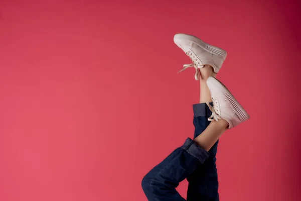 Kvinnliga ben upp och ner i vita sneakers rosa bakgrund mode — Stockfoto