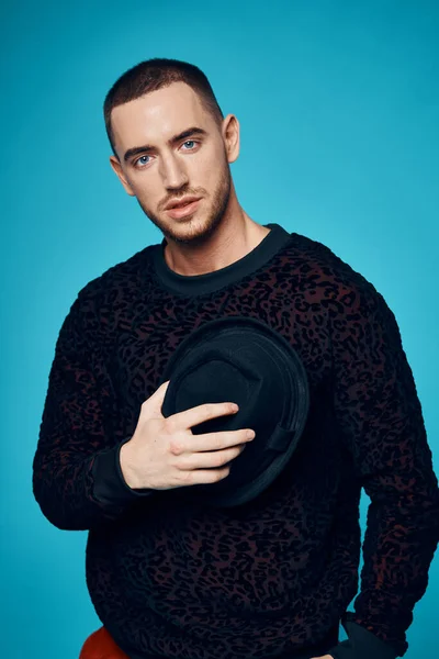 Homem de camisola preta bonés posando moda estúdio azul fundo — Fotografia de Stock