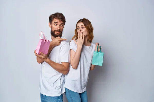 Emotionele mannen en vrouwen in t-shirts pakketten met geschenken vakantie lichte achtergrond — Stockfoto