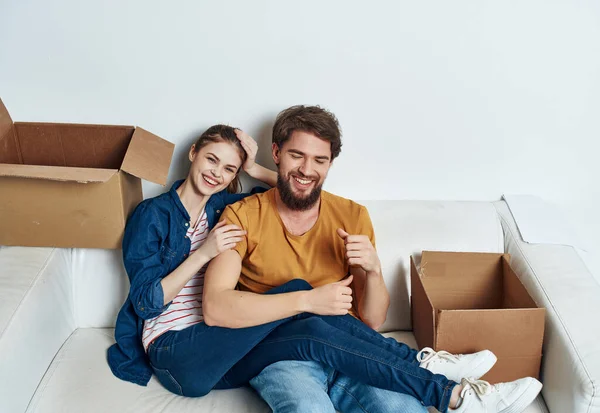 Άνδρας και γυναίκα κάθονται στον καναπέ μεταφέροντας κουτιά με πράγματα που ζεσταίνουν την οικογένεια — Φωτογραφία Αρχείου