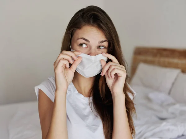 Frau mit medizinischer Maske sitzt auf Bett im Hotel — Stockfoto