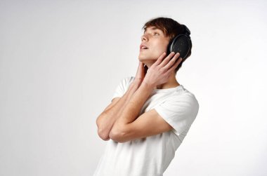 Kulaklık takan beyaz tişörtlü adam. Müzik teknolojisi arka planda.