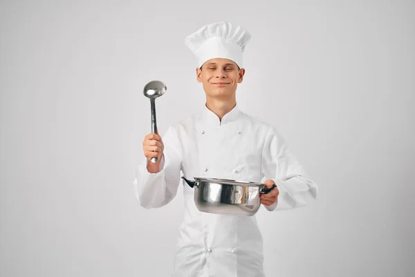 Uomo in abiti da chef con una casseruola in mano preparare cibo sfondo luce — Foto Stock