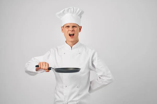 Homme dans les chefs vêtements poêle à frire dans les mains cuisine professionnels travaillent — Photo