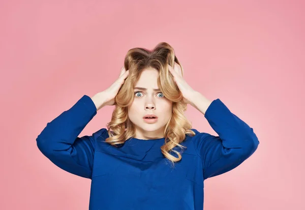 Pirang emosional dalam gaun biru memegang kepalanya ketidakpuasan latar belakang merah muda — Stok Foto
