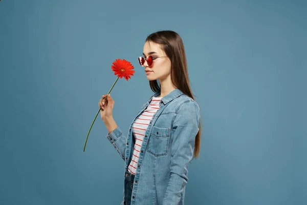 Atrakcyjna kobieta nosi okulary czerwony kwiat dekoracji moda niebieski tło — Zdjęcie stockowe