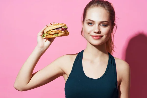 Sport kobieta trening hamburger fast food dieta różowy tło — Zdjęcie stockowe
