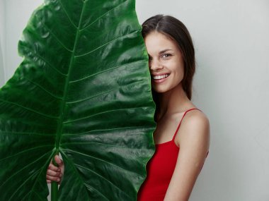 Yüzünün yarısını palmiye yaprağı stüdyosuyla örten mayo giymiş bir kadın.
