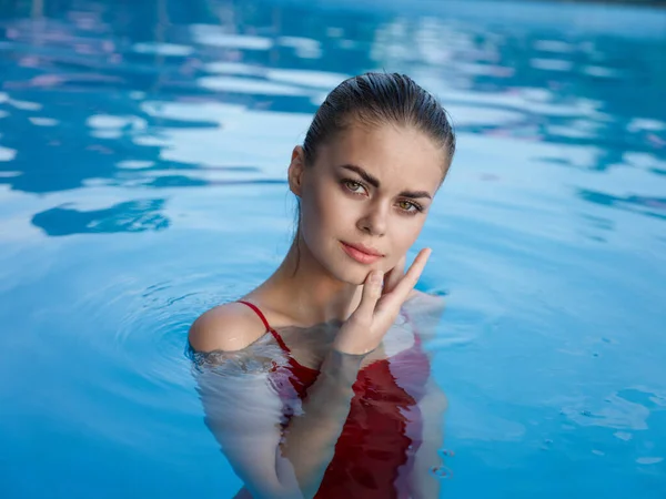 Женщина в красном купальнике в бассейне держит руку возле лица — стоковое фото