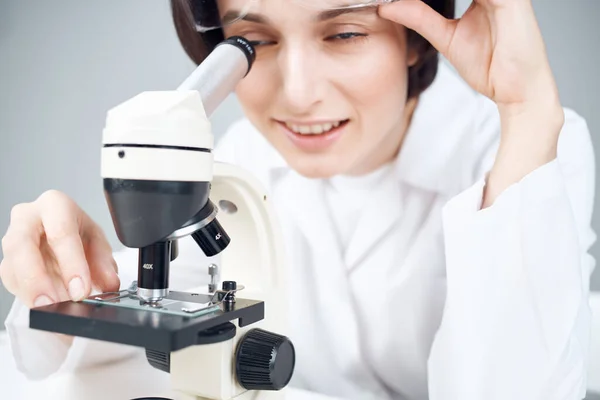 Uno scienziato con un mantello bianco che guarda attraverso un laboratorio di primo piano al microscopio — Foto Stock