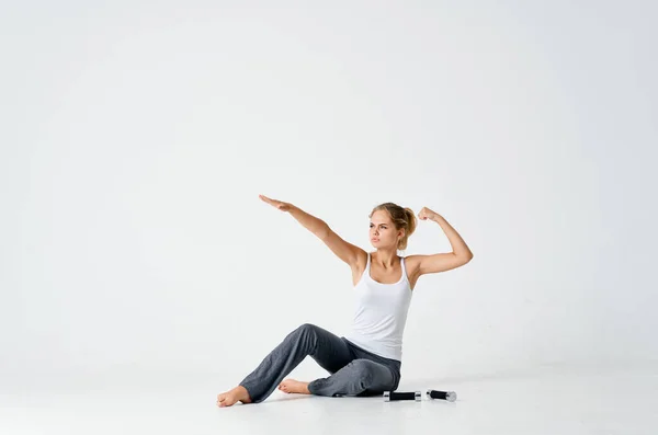Спортивна жінка сидить на підлозі гантелі в руках, заряджаючи мотивацію енергетичними вправами — стокове фото