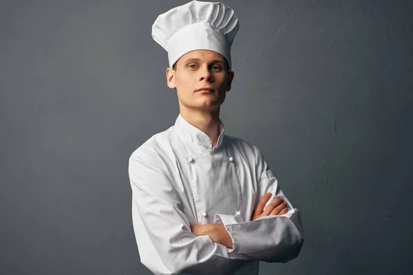 Chef professionista con espressione seria si tiene per mano di fronte a lui sfondo scuro — Foto Stock