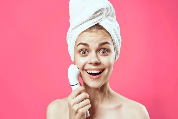 Жінка з рушником на голові голі плечі догляд за шкірою косметологія рожевий фон — стокове фото
