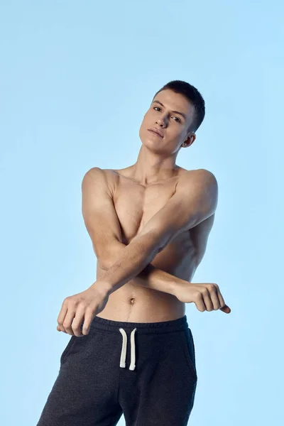 Sportig man med naken överkropp korsade armarna framför honom poserar i blå bakgrund — Stockfoto