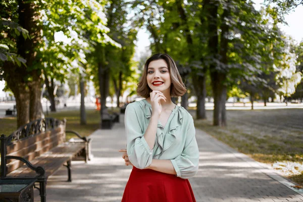 Hezká žena v červené sukni v parku chodit životní styl čerstvý vzduch — Stock fotografie