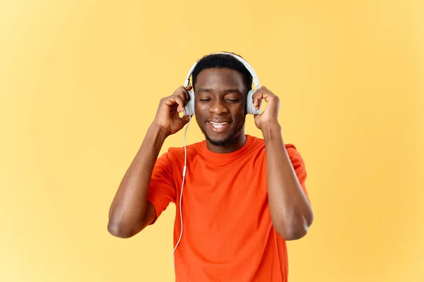 Hombre en camiseta naranja con auriculares escuchando música — Foto de Stock
