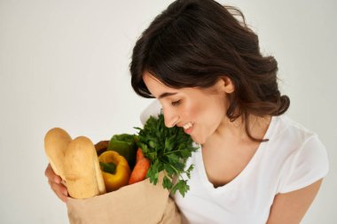 Esmer, beyaz tişörtlü, içinde bakkaliye ve sağlıklı yiyecek paketi olan. Yakın çekim.