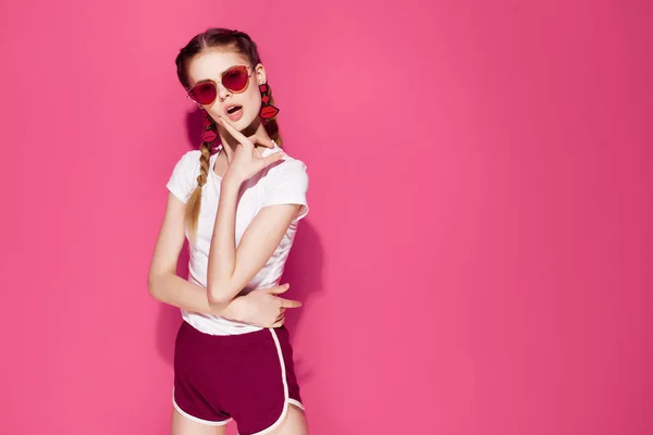 Bella donna indossa occhiali da sole glamour trecce stile di vita moda rosa sfondo — Foto Stock