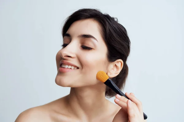 Pretty brunette applying makeup on face close-up naked shoulders — Stock Photo, Image