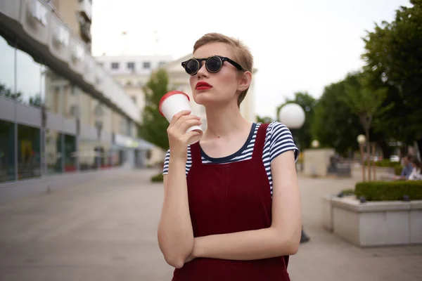 Bonita mujer con gafas al aire libre caminando café en las manos — Foto de Stock