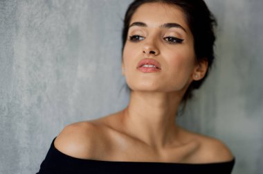 Siyah elbiseli kadın kozmetik dekorasyon pozu veriyor.