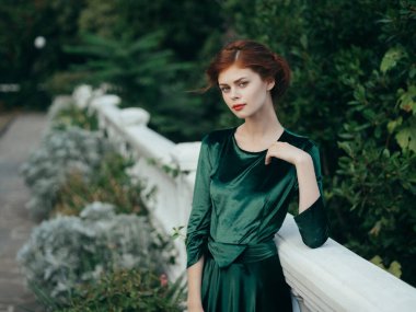 Yeşil elbiseli çekici bir kadın. Kırmızı dudaklı. Park yazı.