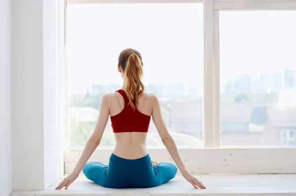 Kvinna nära fönstret träna yoga asana motion — Stockfoto