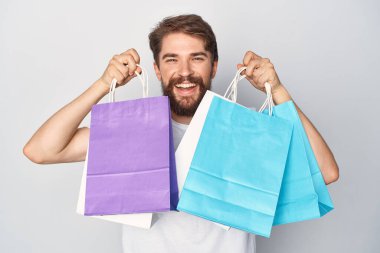 Elinde paketlerle neşeli sakallı bir adam. Duygularını alışverişe yakın tutuyor.