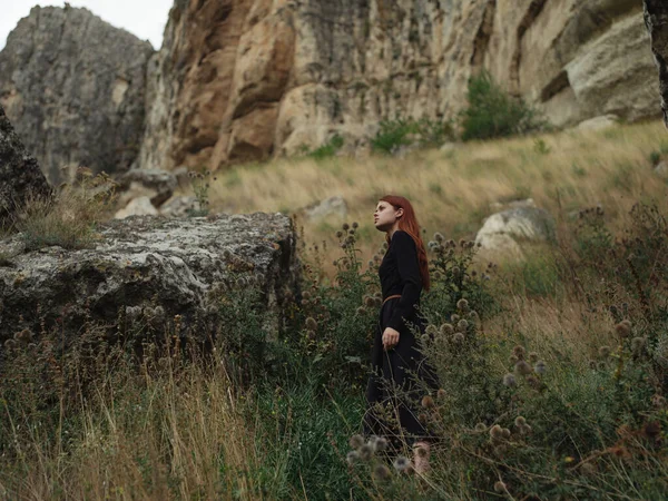 Mujer con el pelo rojo en un vestido negro montañas naturaleza viaje —  Fotos de Stock